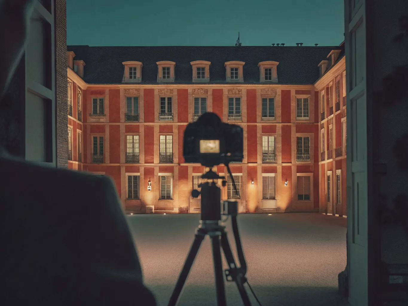 Hotel brand and visual storytelling: camera on a tripod capturing an illuminated boutique hotel courtyard at dusk
