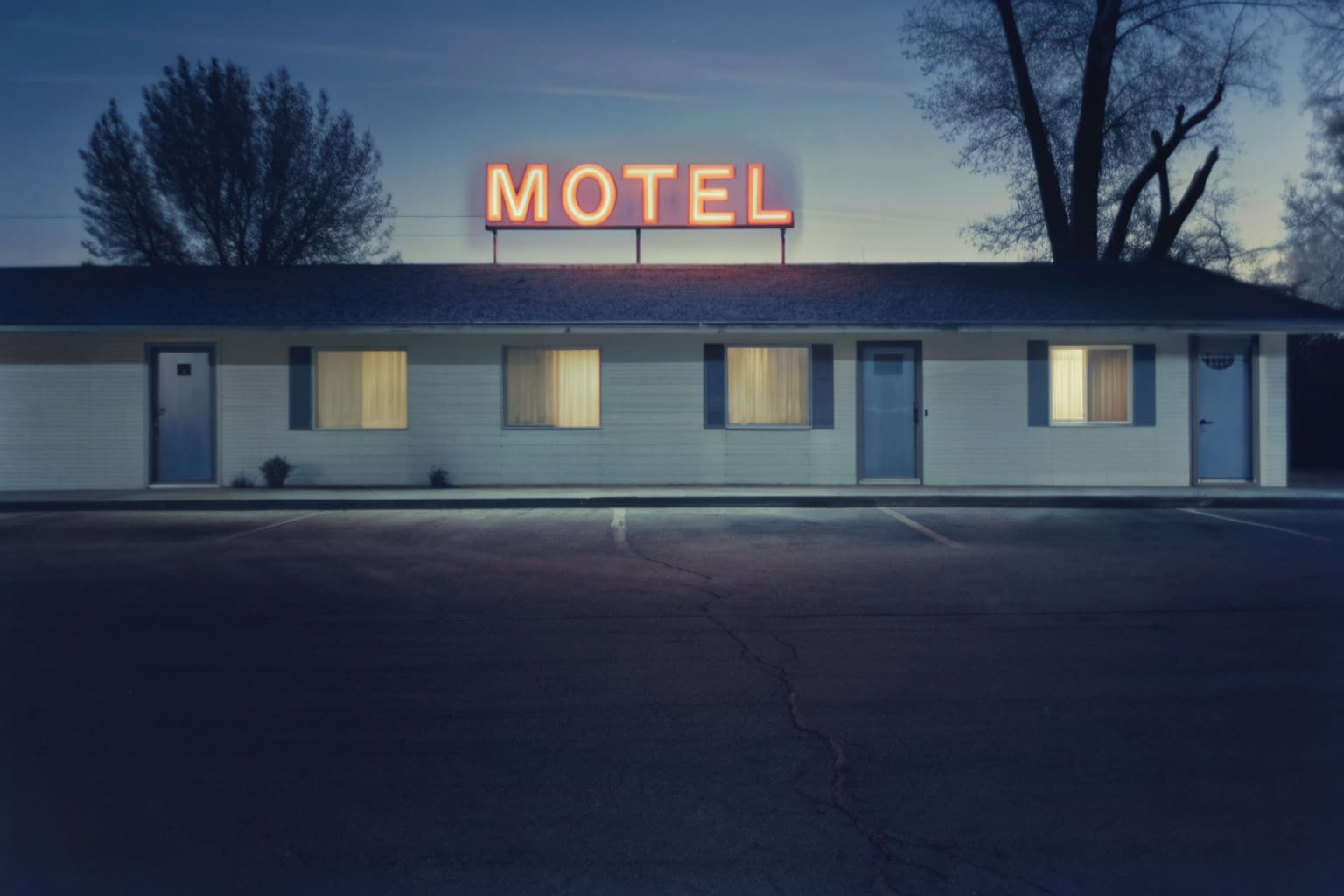 Roadside motel exterior at dusk with glowing neon motel sign