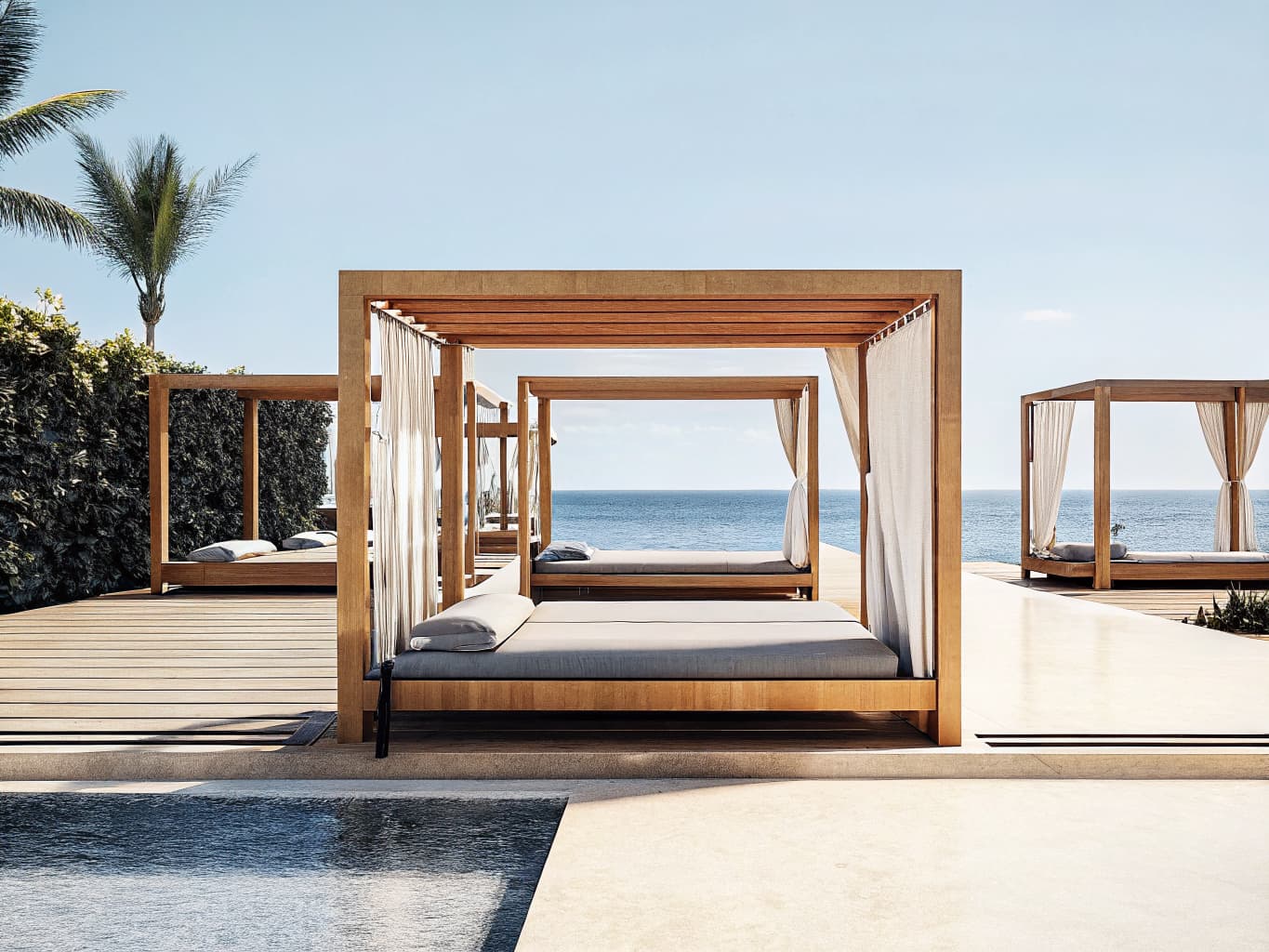 Upscale tropical resort pool deck with cabanas and ocean view